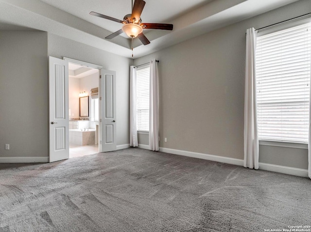 carpeted spare room featuring ceiling fan and a raised ceiling