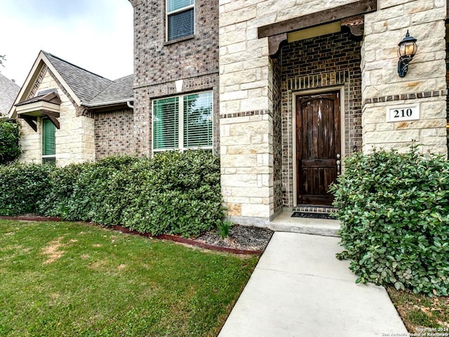 view of exterior entry featuring a lawn