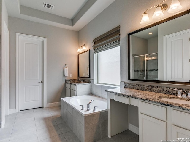 bathroom with a raised ceiling, vanity, tile floors, and tiled bath