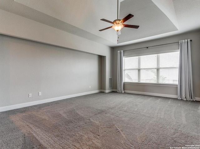 spare room featuring lofted ceiling, ceiling fan, carpet floors, and a tray ceiling