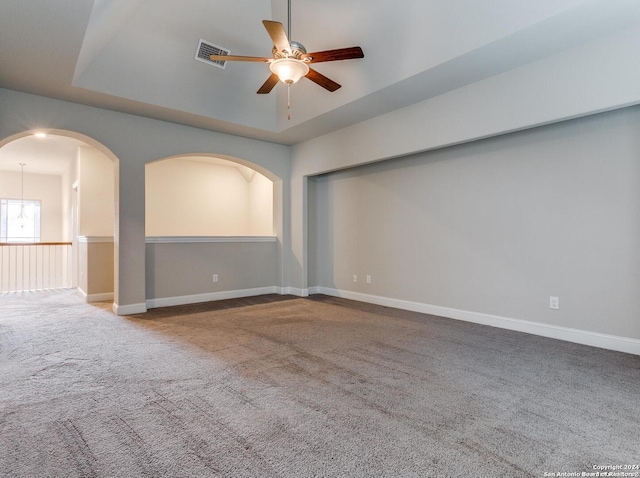 spare room featuring a tray ceiling, ceiling fan, and carpet