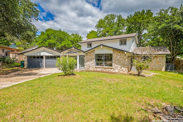 view of property featuring central AC unit, a front lawn, and a garage