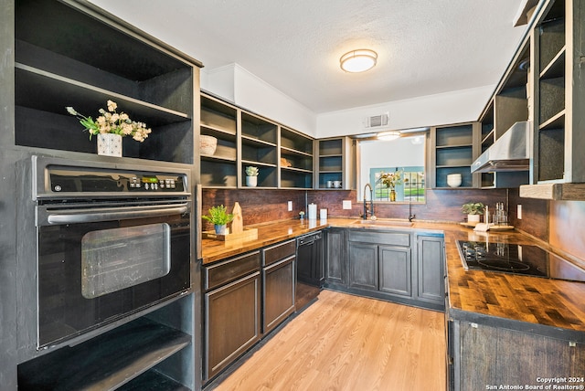 kitchen featuring wall chimney exhaust hood, black appliances, sink, light hardwood / wood-style floors, and butcher block counters