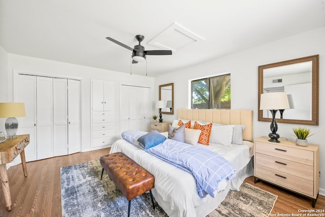 bedroom featuring light hardwood / wood-style floors, ceiling fan, and two closets