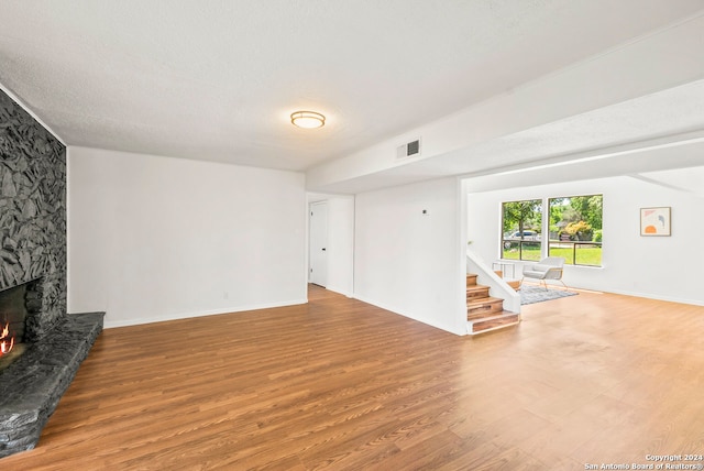 living room featuring hardwood / wood-style flooring, a fireplace, and a textured ceiling