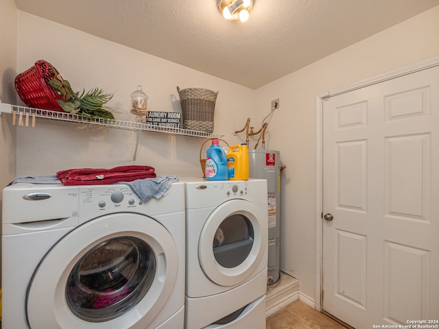 washroom with a textured ceiling, electric water heater, washing machine and dryer, and light tile patterned flooring