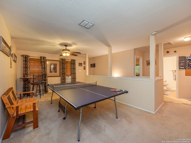 recreation room with ceiling fan, light colored carpet, and a textured ceiling