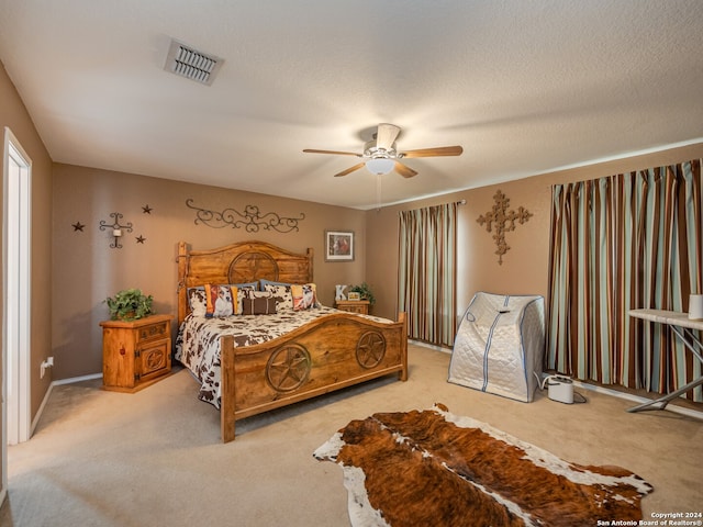 carpeted bedroom with ceiling fan and a textured ceiling