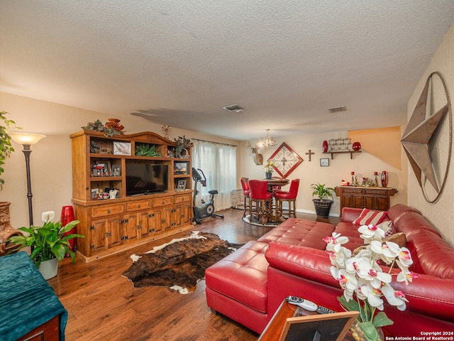 living room with hardwood / wood-style floors, a textured ceiling, and a notable chandelier