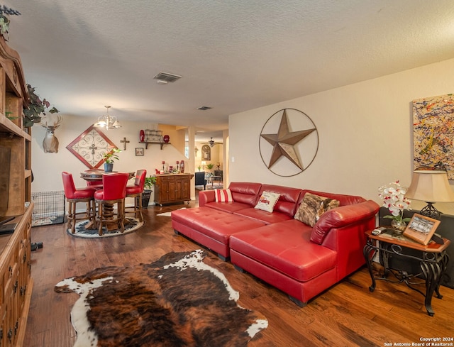 living room featuring hardwood / wood-style flooring, a textured ceiling, and an inviting chandelier