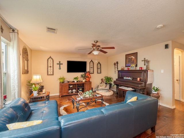 living room with dark hardwood / wood-style floors, ceiling fan, and a textured ceiling