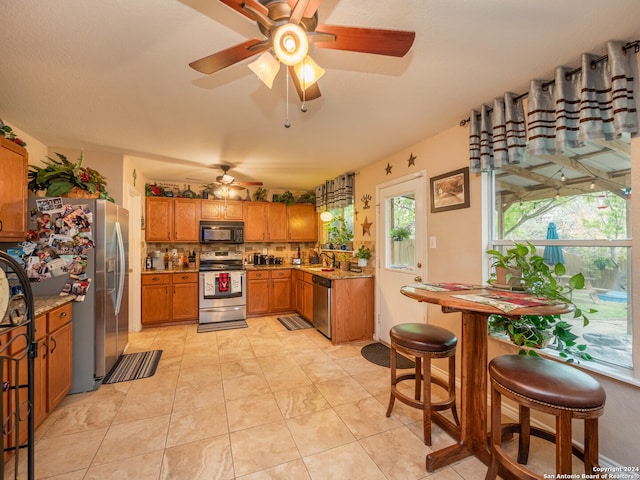 kitchen with tasteful backsplash, stainless steel appliances, ceiling fan, sink, and light tile patterned floors