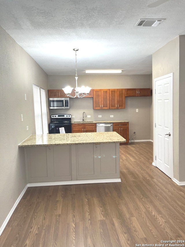 kitchen featuring hanging light fixtures, dark hardwood / wood-style floors, stainless steel appliances, and kitchen peninsula