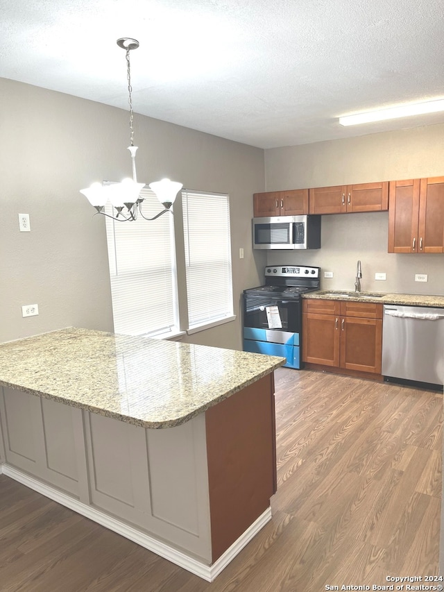 kitchen featuring hardwood / wood-style floors, appliances with stainless steel finishes, pendant lighting, and an inviting chandelier