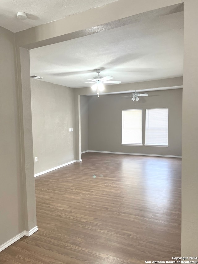 empty room featuring ceiling fan, dark hardwood / wood-style floors, and a textured ceiling