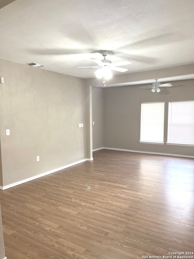 empty room featuring a textured ceiling, ceiling fan, and dark wood-type flooring