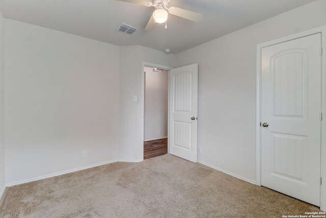 empty room featuring ceiling fan and light carpet