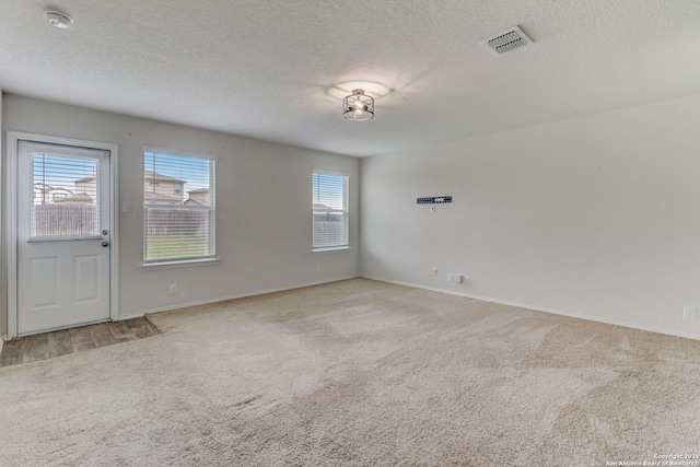 unfurnished room featuring a textured ceiling, plenty of natural light, and light carpet