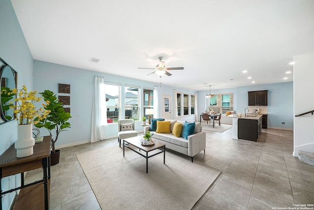 tiled living room featuring a wealth of natural light, ceiling fan, and sink