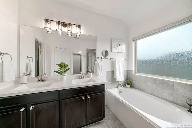 bathroom with double sink vanity, lofted ceiling, tile floors, and a bathing tub