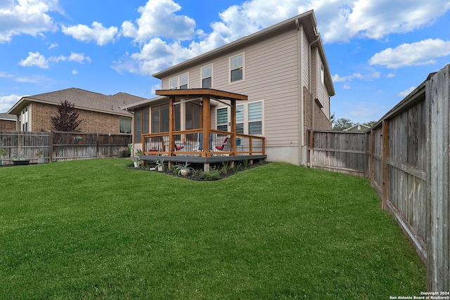 rear view of house with a wooden deck, a yard, and a sunroom