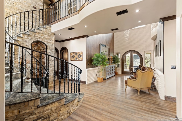 entryway featuring hardwood / wood-style floors, french doors, crown molding, and a towering ceiling