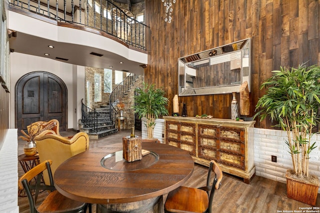 dining area featuring dark hardwood / wood-style flooring, wooden walls, and a towering ceiling