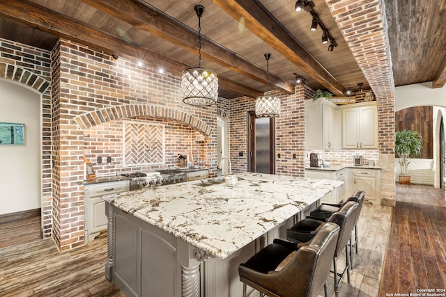 kitchen with wood ceiling, a center island with sink, and track lighting