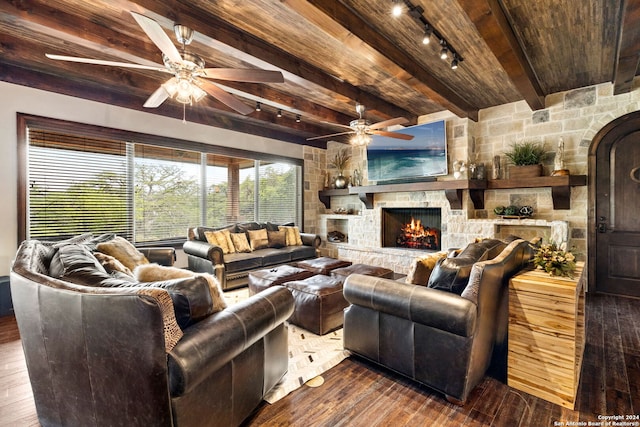 living room featuring hardwood / wood-style floors, rail lighting, beam ceiling, wood ceiling, and a stone fireplace