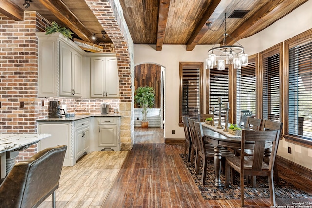 dining space featuring an inviting chandelier, beamed ceiling, wooden ceiling, and light wood-type flooring