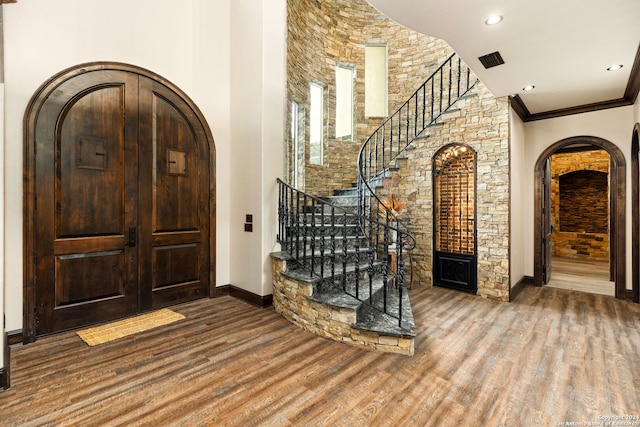 foyer featuring wood-type flooring and a towering ceiling