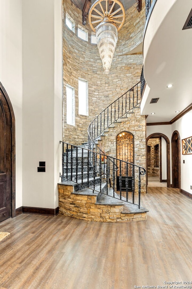 foyer featuring a chandelier, crown molding, wood-type flooring, and a high ceiling