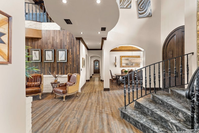 entrance foyer with ornamental molding, a towering ceiling, and hardwood / wood-style flooring