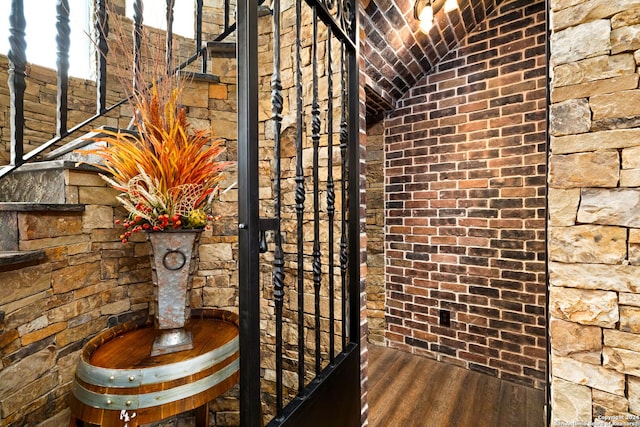 wine cellar with brick wall and hardwood / wood-style floors