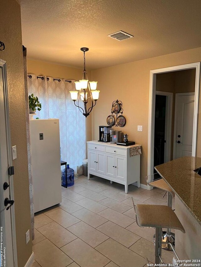 tiled dining room with a notable chandelier and a textured ceiling