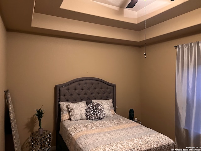 bedroom with ceiling fan and a tray ceiling