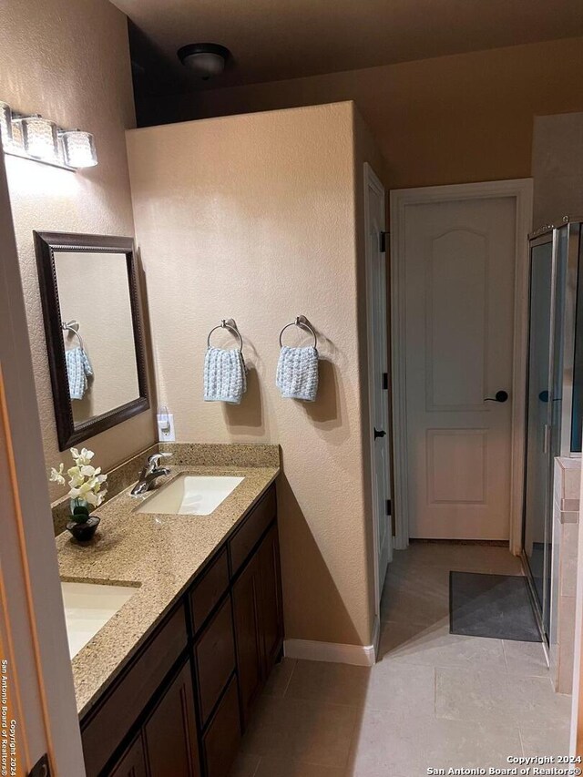 bathroom with large vanity, an enclosed shower, dual sinks, and tile flooring