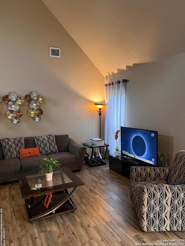 living room with high vaulted ceiling and hardwood / wood-style floors