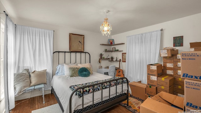 bedroom with dark wood-type flooring and an inviting chandelier