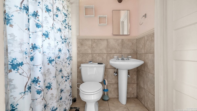 bathroom featuring tile walls, sink, toilet, and tile flooring