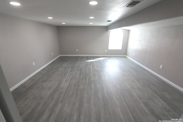 empty room with dark hardwood / wood-style floors and a textured ceiling