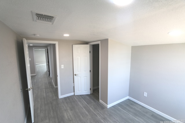 unfurnished bedroom with dark wood-type flooring and a textured ceiling