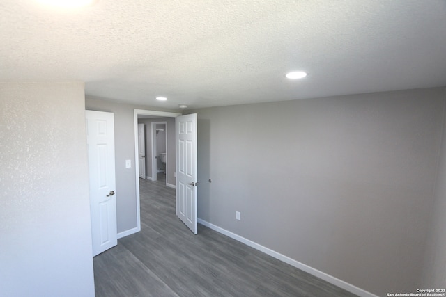 spare room featuring dark wood-type flooring and a textured ceiling