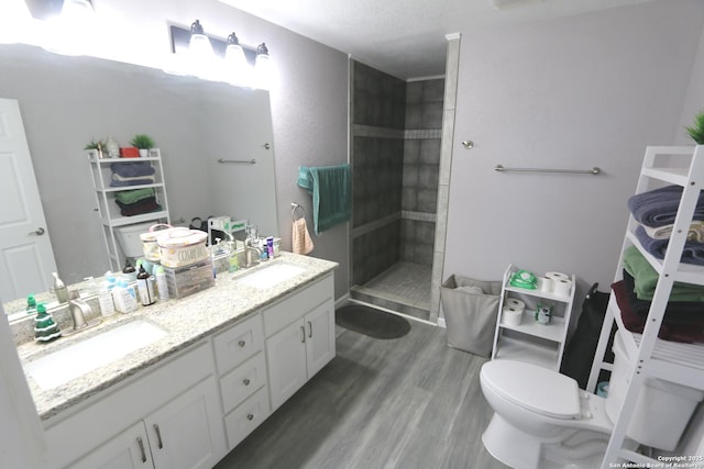 bathroom featuring vanity, hardwood / wood-style flooring, toilet, and tiled shower