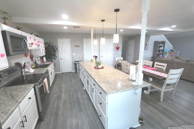 kitchen featuring a kitchen bar, white cabinetry, dark hardwood / wood-style flooring, pendant lighting, and stainless steel appliances