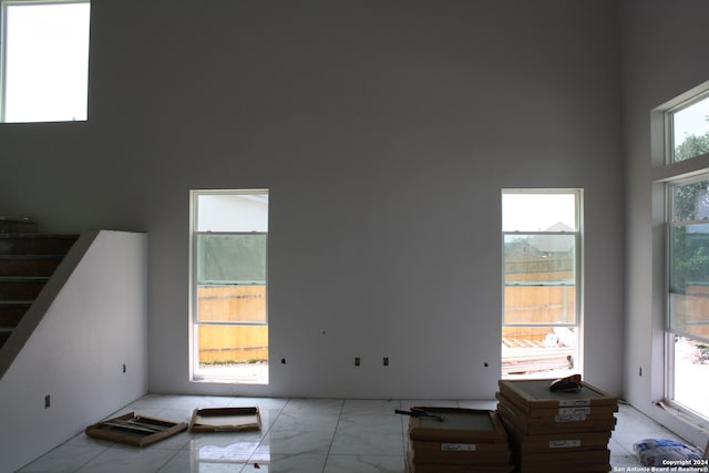 living room with a towering ceiling, marble finish floor, and stairway