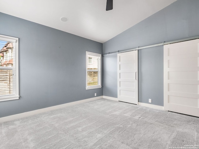 unfurnished bedroom with carpet flooring, lofted ceiling, multiple windows, and ceiling fan