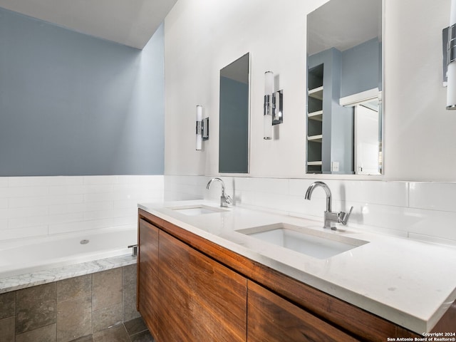 bathroom with tile flooring, tiled tub, backsplash, oversized vanity, and dual sinks