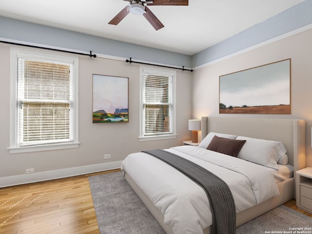 bedroom with ceiling fan, light hardwood / wood-style flooring, and multiple windows