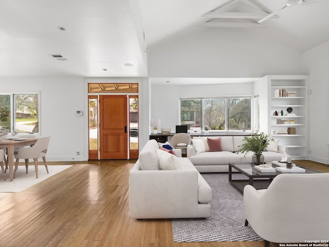 living room featuring high vaulted ceiling and wood-type flooring